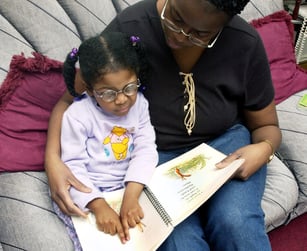 Mother and daughter sitting together, reading a braille book.
