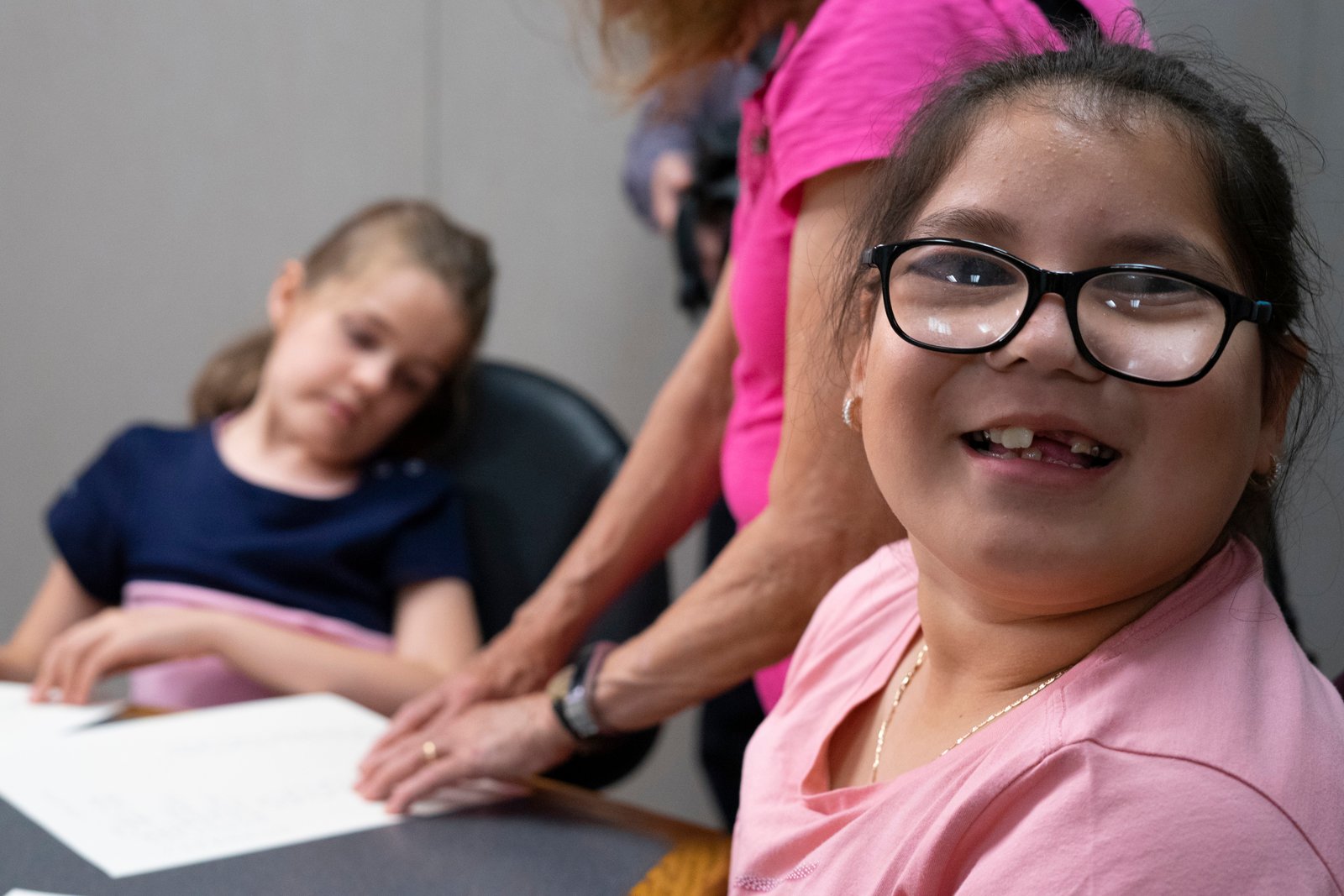 A young girl smiling for the camera during a braille lesson.-1