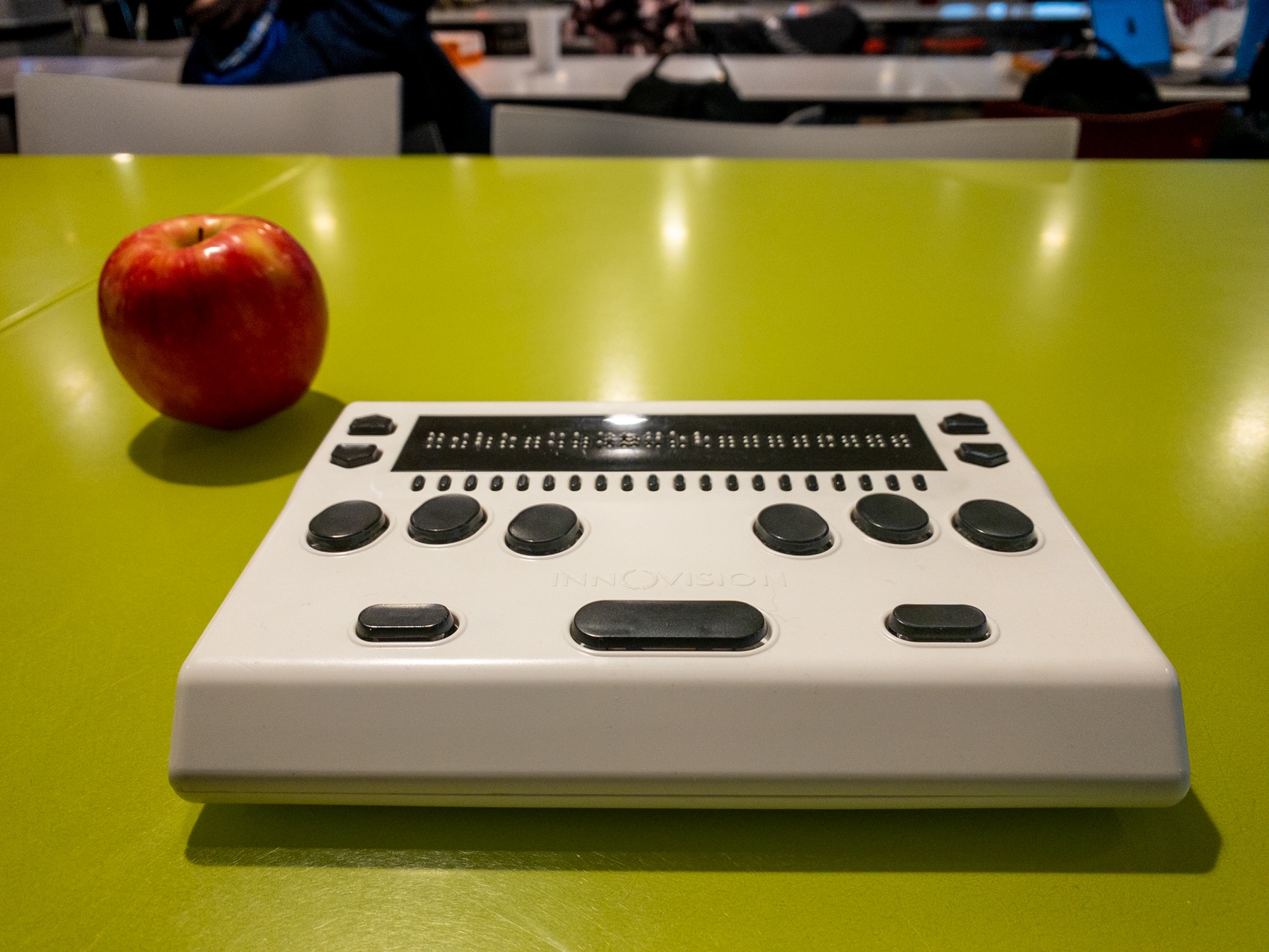 The Braille Me Refreshable Braille Display on a bright green table.